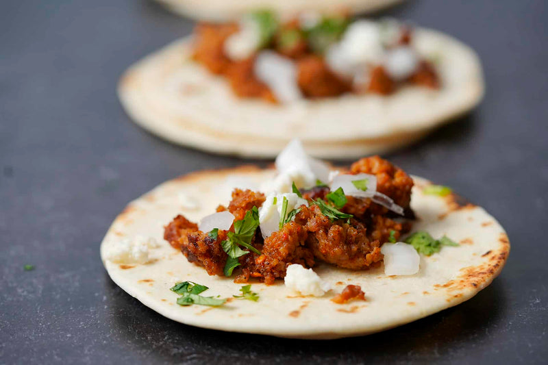 Tortilla with meat and toppings on a dark surface