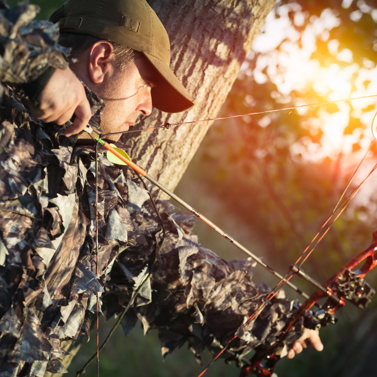 a hunter drawing a bow in the woods