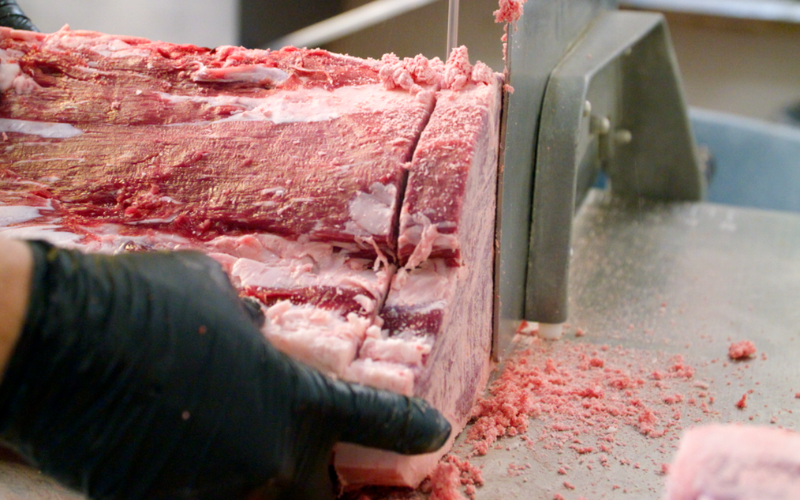 cutting a beef porterhouse steak with a bandsaw