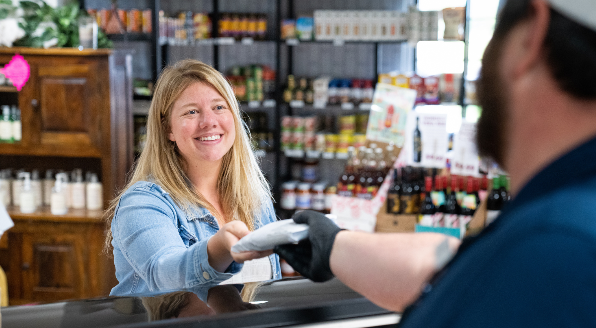 Woman at a meat counter in a store taking a steak from a clerk.