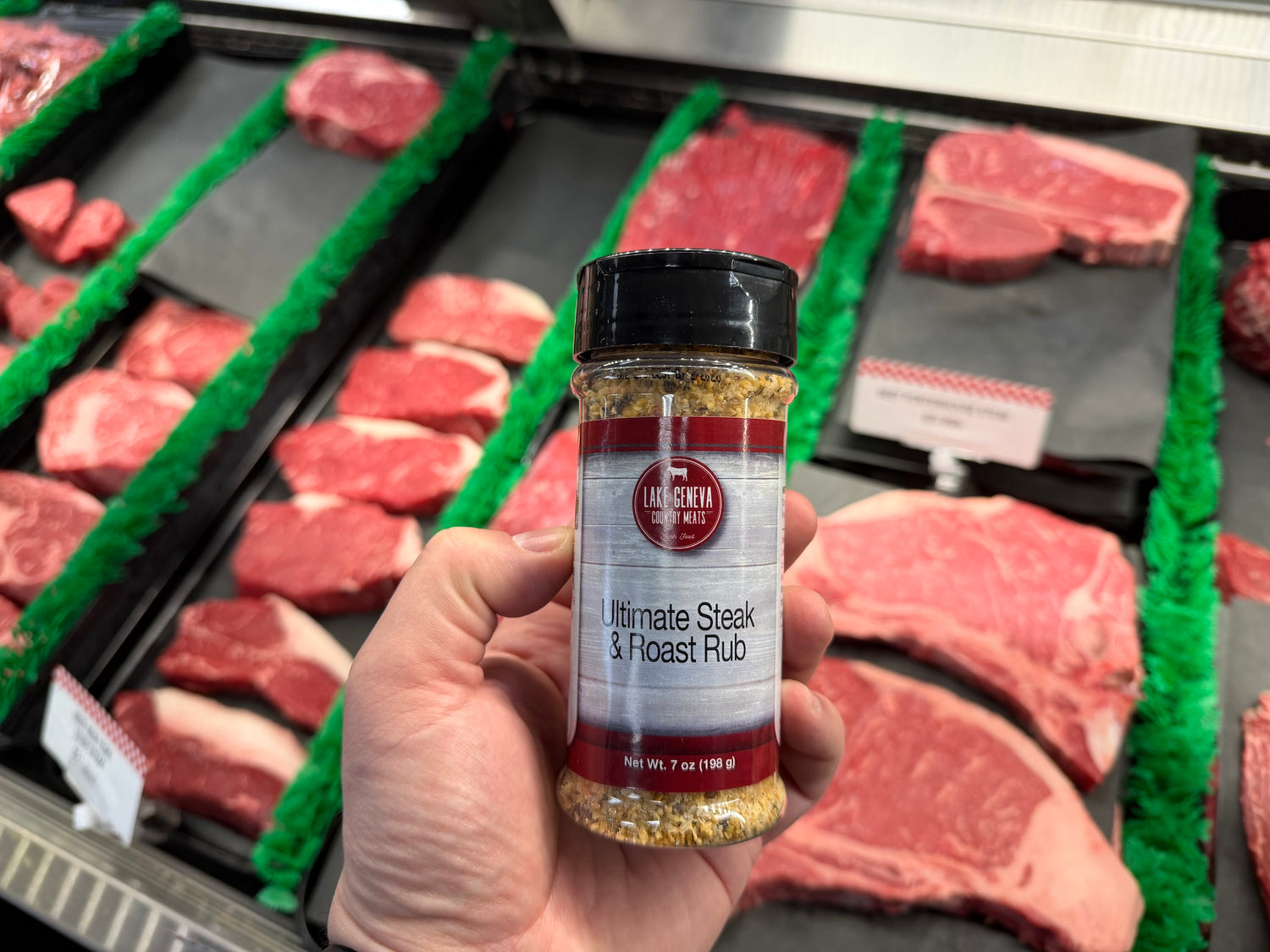 a bottle of LGCM Ultimate Steak & Roast Rub over raw steaks