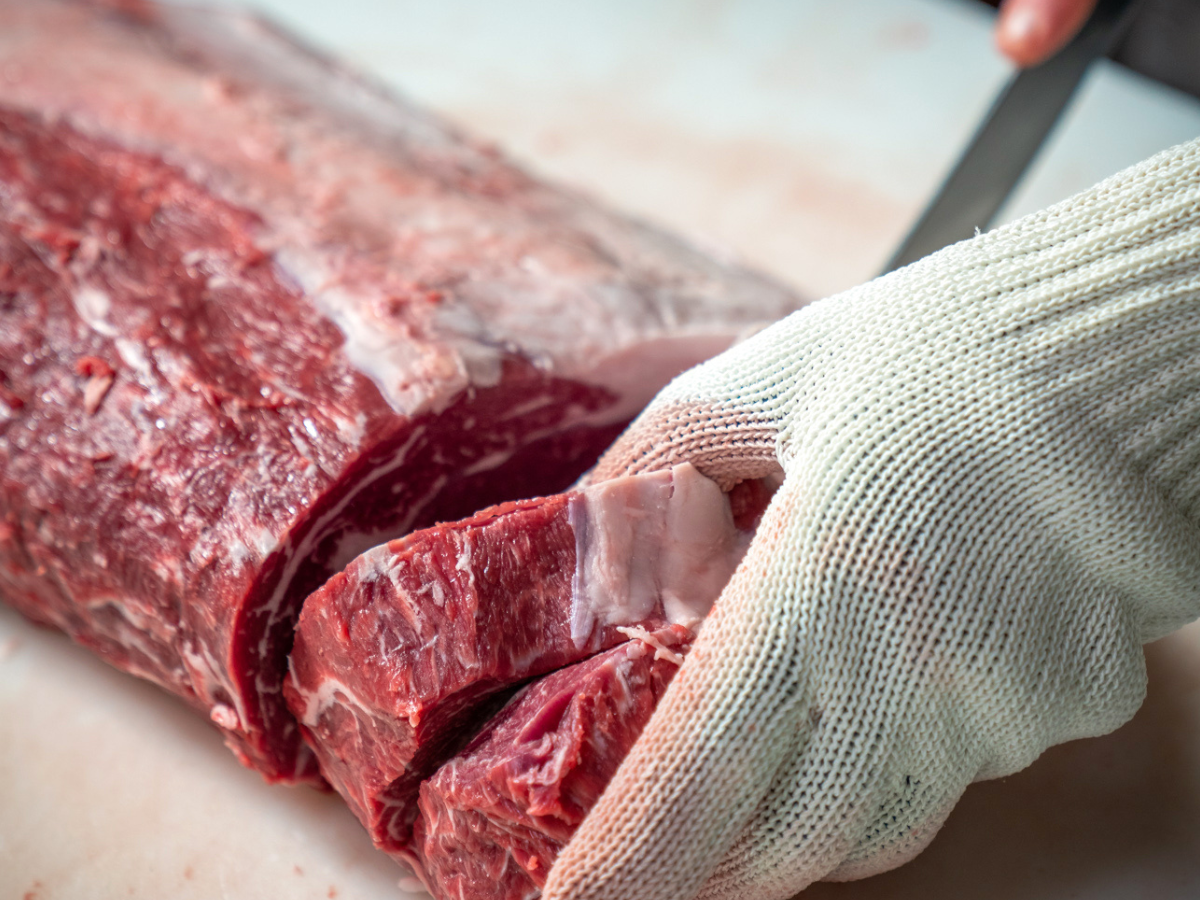 A butcher cutting ribeye steaks