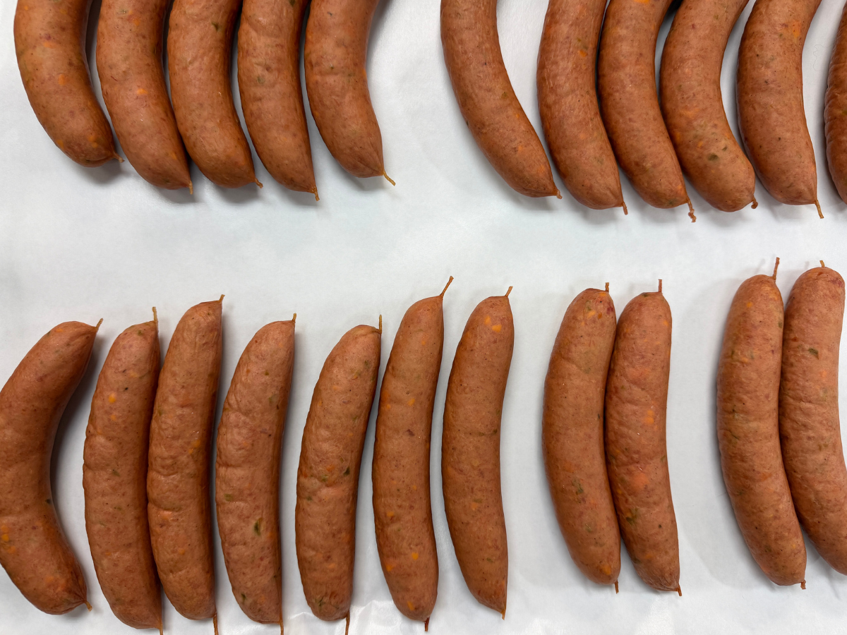 Multiple sausages arranged in rows on a white surface