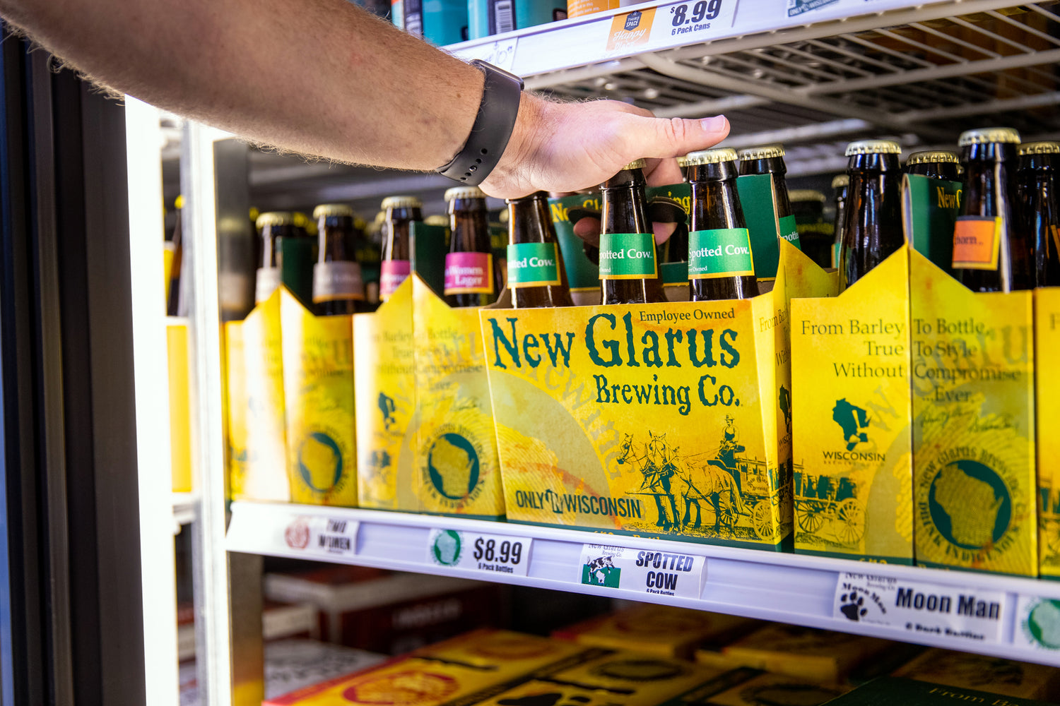 a six pack of spotted cow beer on a cooler shelf