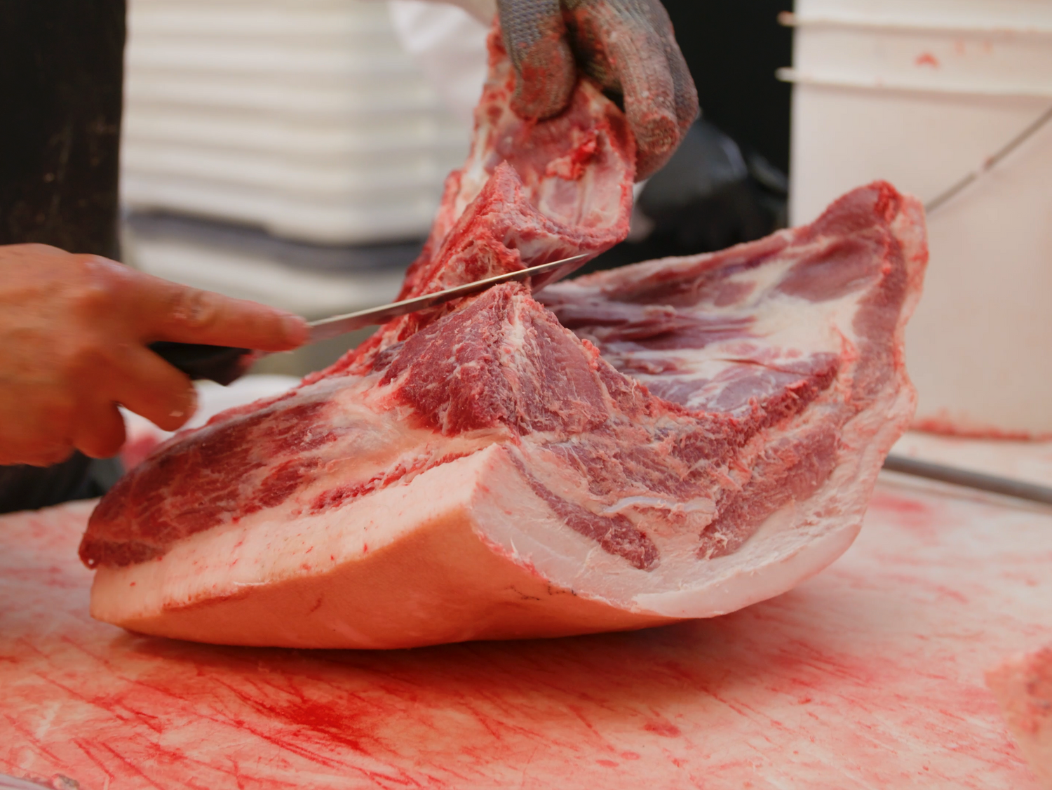 a butcher's knife cutting pork shoulder meat