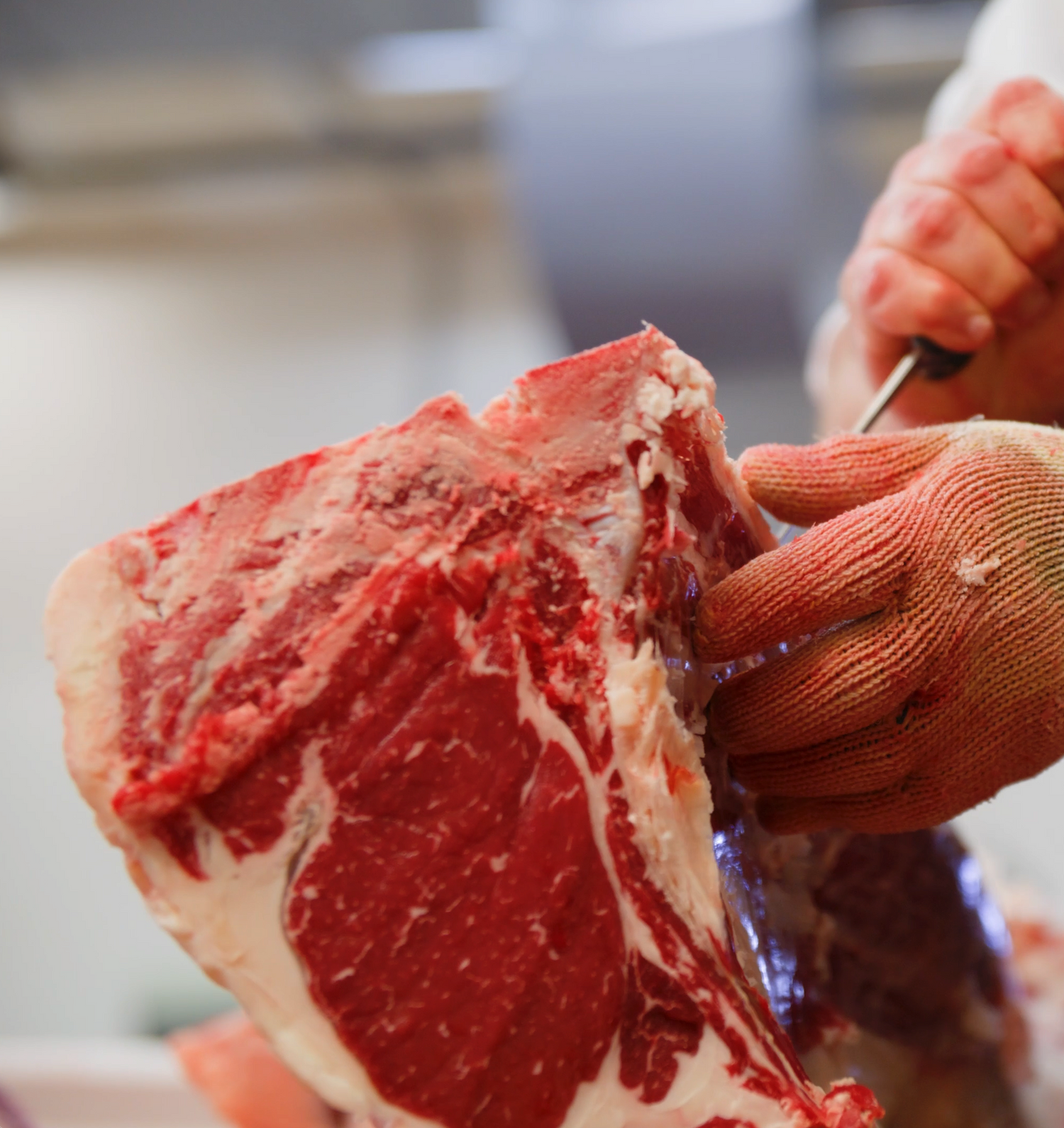 a butcher trimming a beef short loin