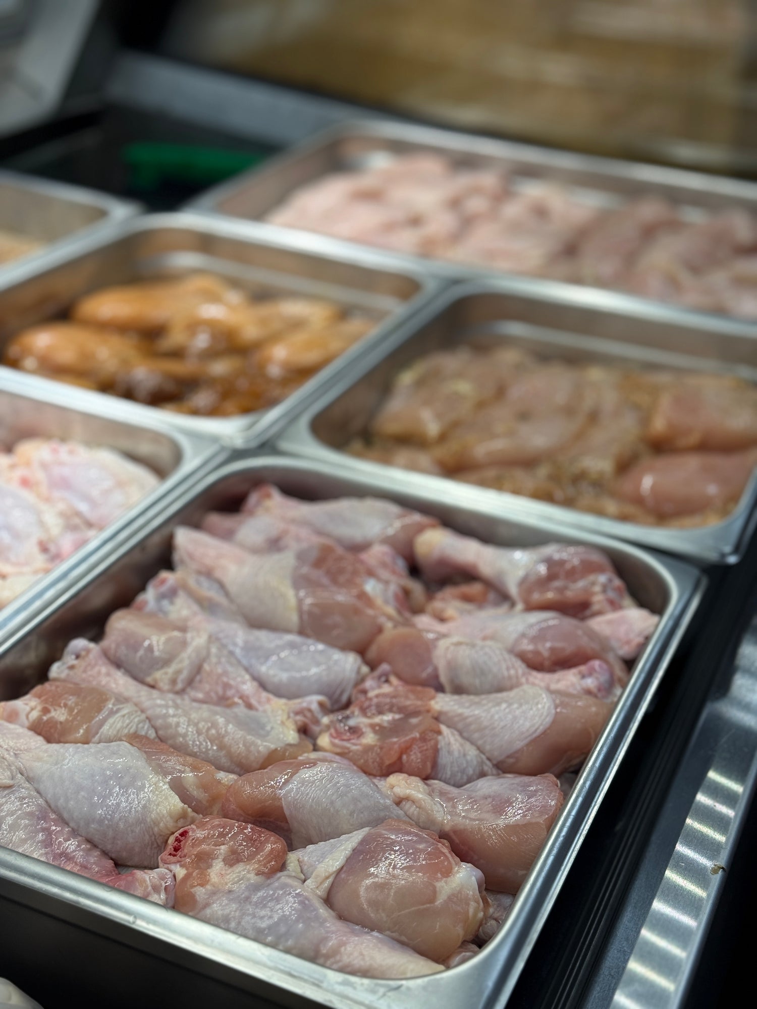 chicken drumsticks in pans in meat case