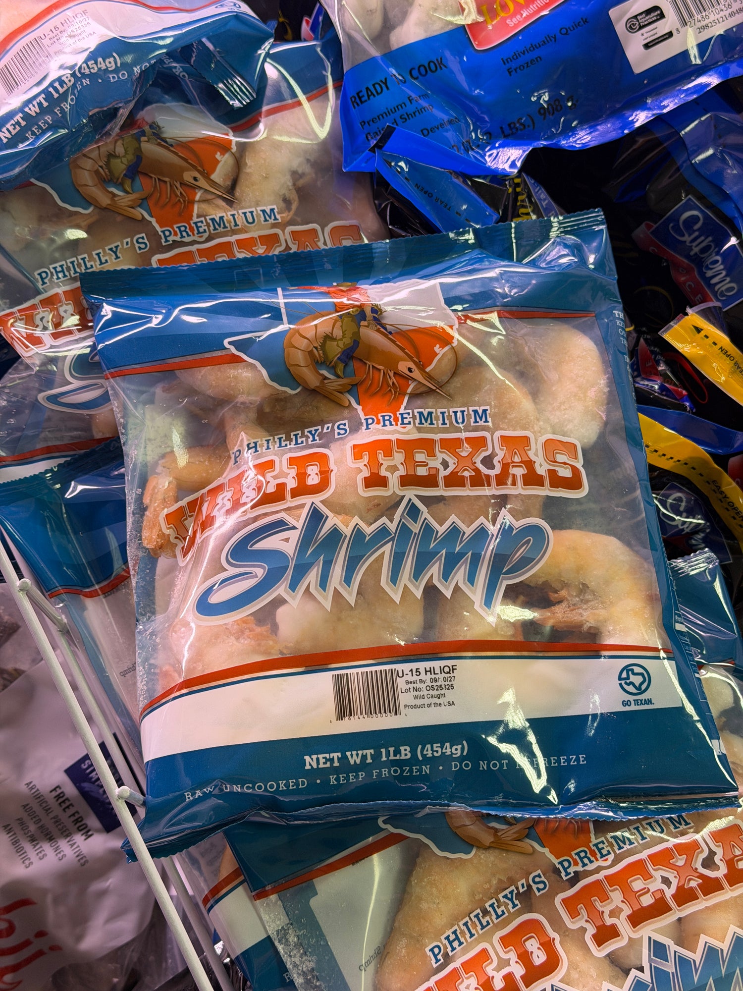 Packaged shrimp with blue and orange branding on a crowded shelf.