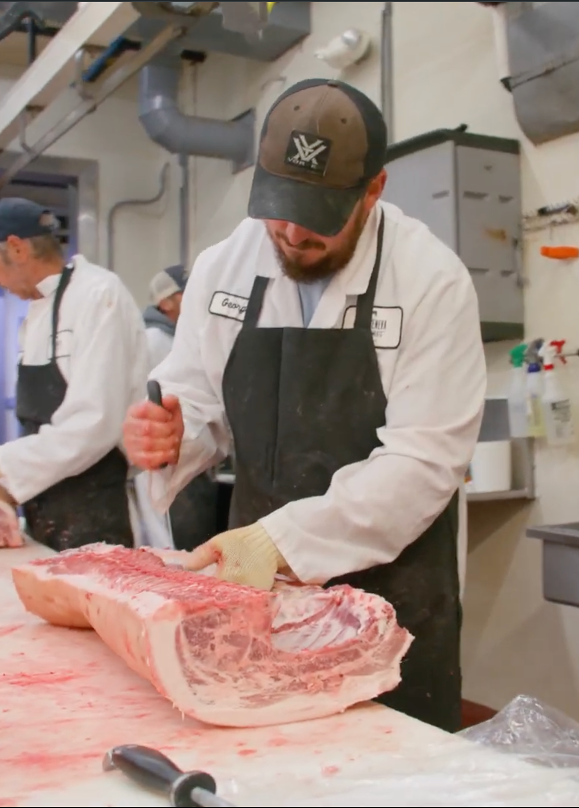 butcher trimming a pork loin carcass