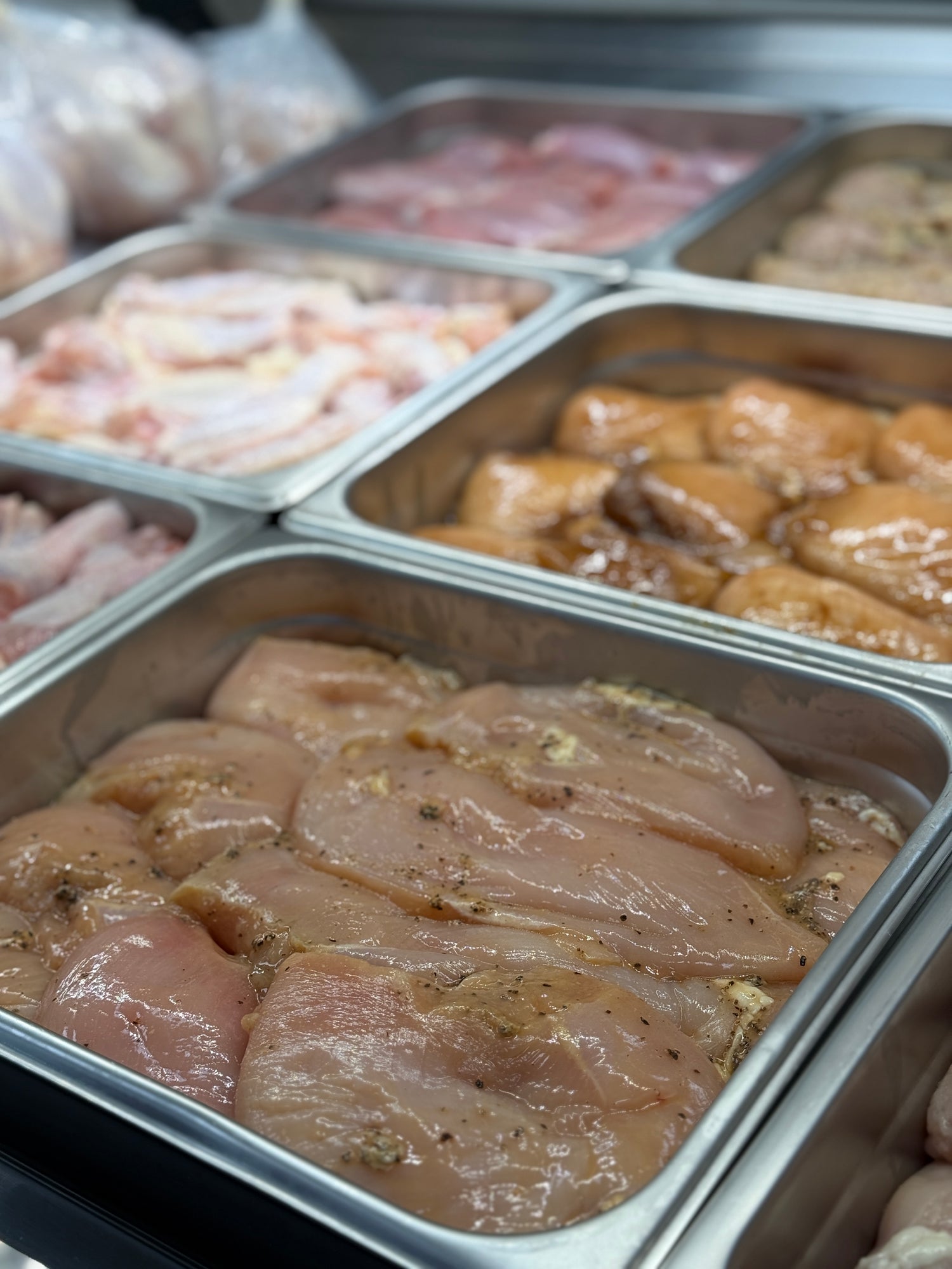 Prepared chicken pieces in metal trays on a kitchen counter