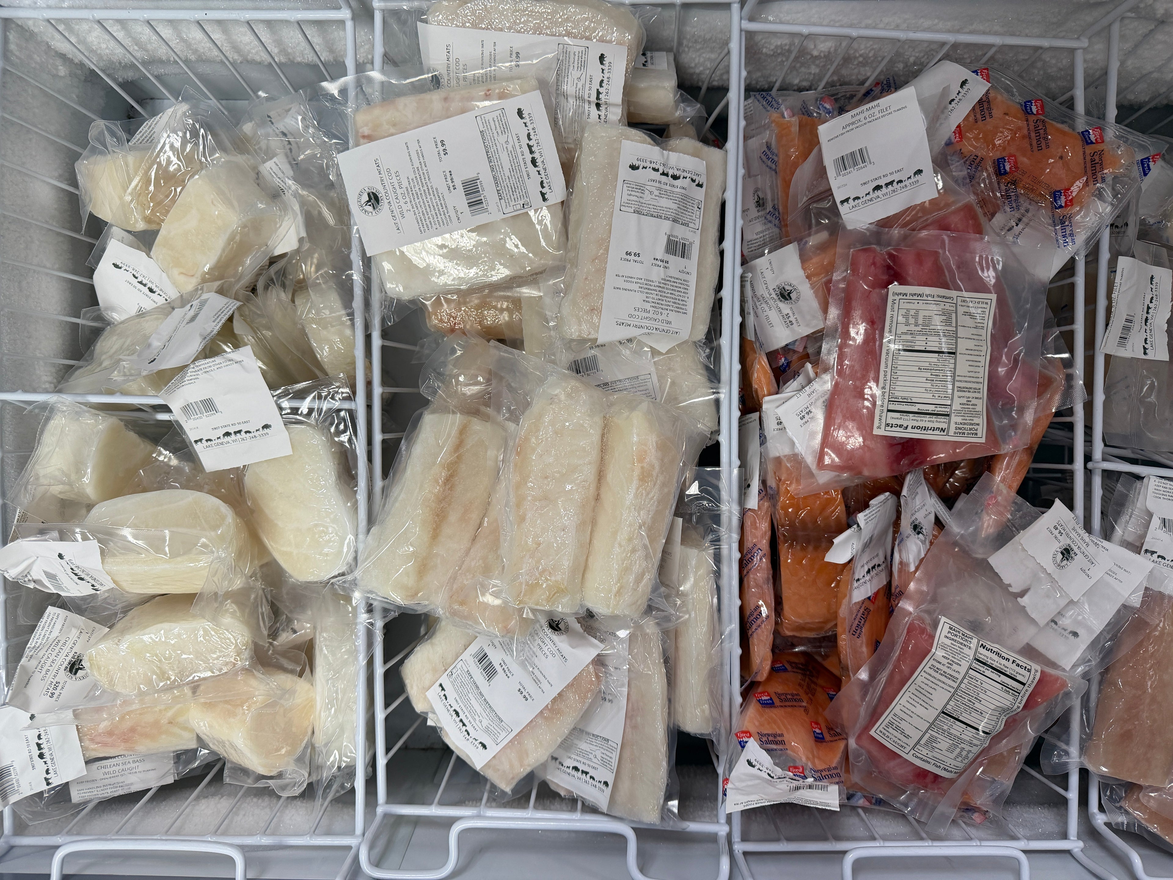 Frozen seafood items in a freezer with labels on packaging