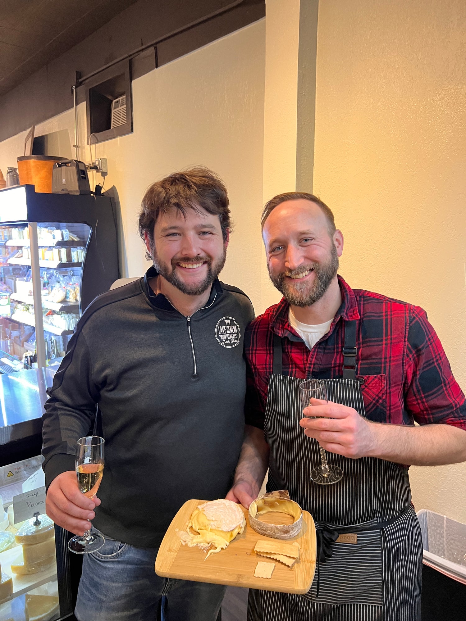 two men holding cheese and wine glasses
