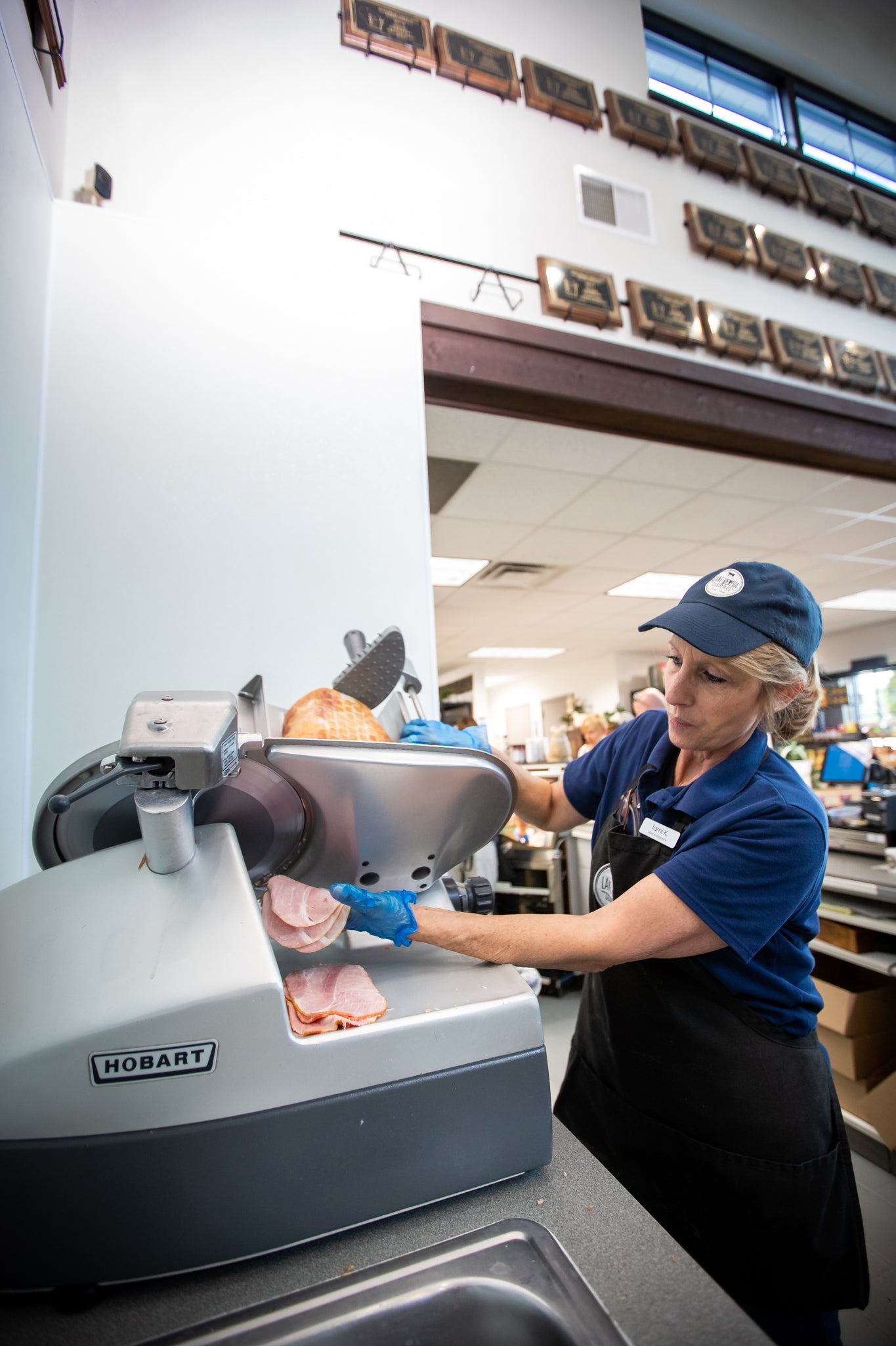person slicing ham on a deli slicer