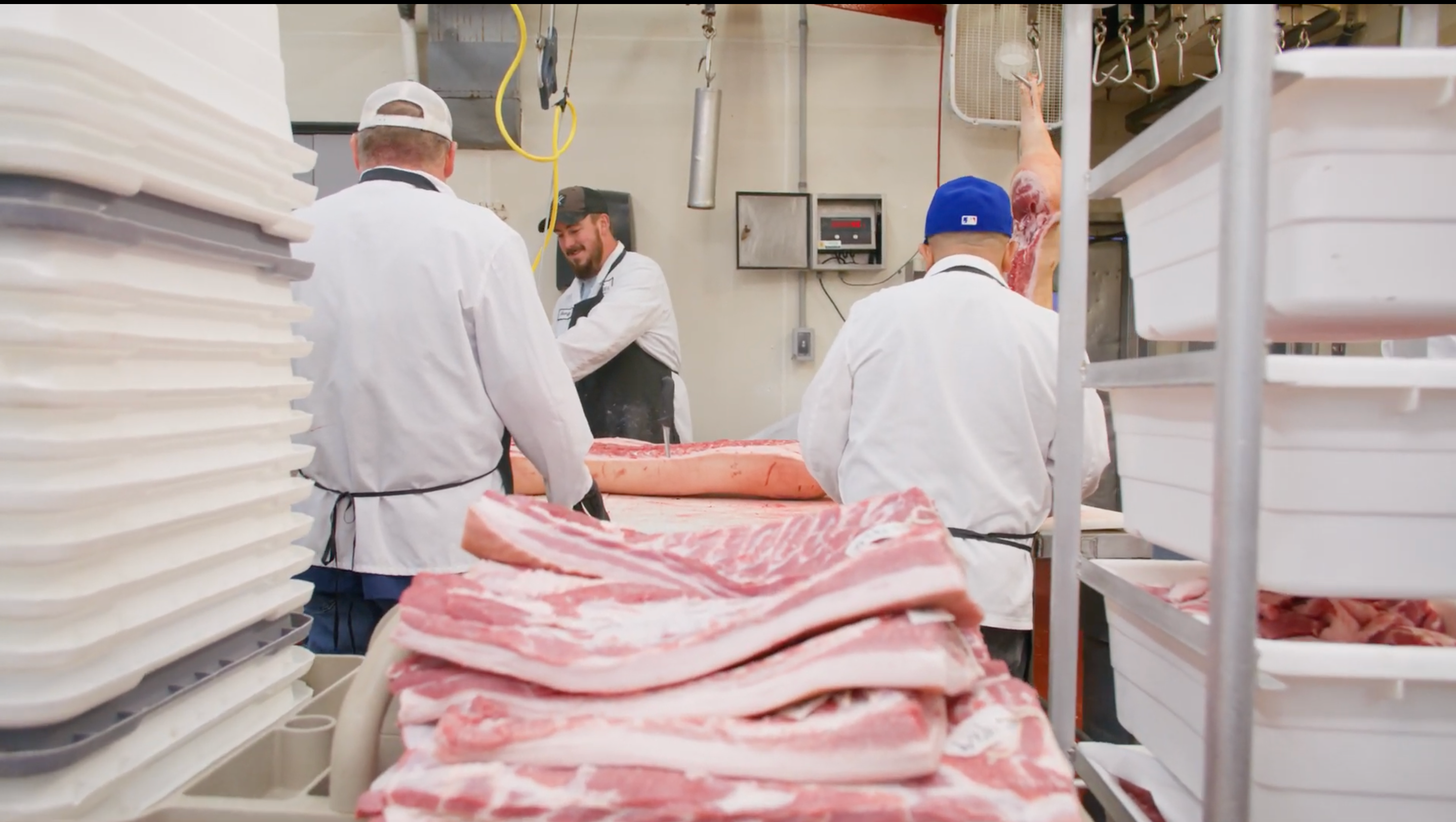 Workers handling pork carcasses in a meat processing plant.