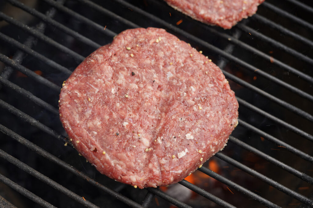 raw hamburger patty on grill